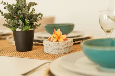 a table with plates and bowls and a flower centerpiece at Stylish 3BR Escape, 5 Mins to Seminyak Beach in Seminyak