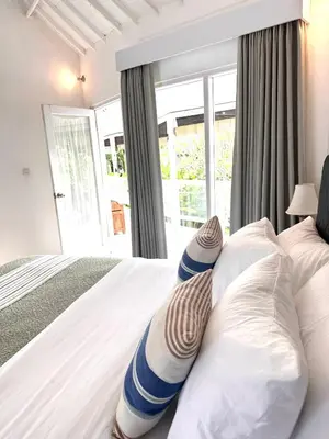 a bedroom with a bed with pillows and a window at Wangi Melati Homestay in Kerobokan