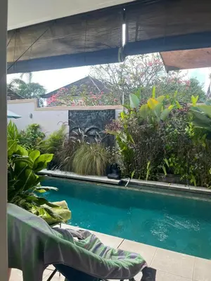 a swimming pool with a bench and some plants at Villa Harmony Moon in Denpasar