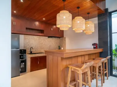 a kitchen with a bar with stools in it at Harbie Villa 2 in Badung