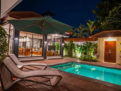 a swimming pool with a chair and an umbrella at Harbie Villa 2 in Badung