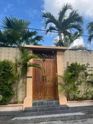 a house with a wooden door and palm trees at Villa Harmony Moon in Seminyak