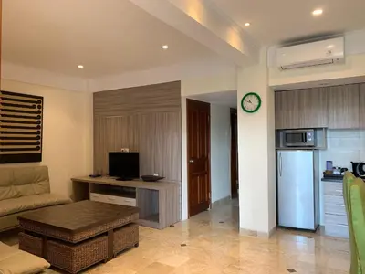 a living room with a couch and a kitchen at The Jayakarta Residence 2BR Bali in Denpasar