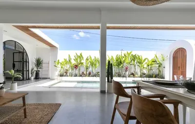 an open kitchen and dining room with a view of a pool at Villa Jiji cozy chic in Bali - just renovated ! in Canggu