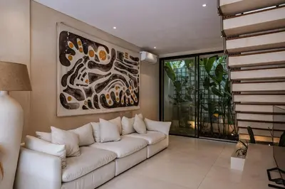 a living room with a white couch and a painting at Villa Nazare Berawa in Canggu