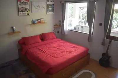 a bedroom with a bed with a red blanket on it at Banana Room Near to Kuta Legian Beach in Legian