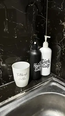 two bottles of detergent and a cup on a sink at Banana Room Near to Kuta Legian Beach in Legian