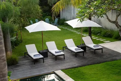a group of chairs and umbrellas on a deck at Villa Semilir Sendja, Canggu in Canggu