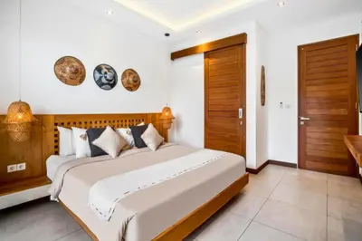 a bedroom with a large bed and wooden doors at Feodora Peaceful 4 BR Private Pool Villa in Seminyak