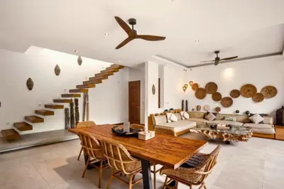 a living room with a wooden table and a staircase at Feodora Peaceful 4 BR Private Pool Villa in Seminyak