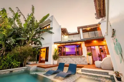 a house with a swimming pool and two blue chairs at Villa Kartini - Two Bedrooms in Legian