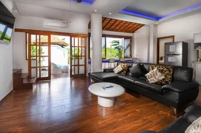 a living room with a black couch and a table at Villa Kartini - Two Bedrooms in Legian