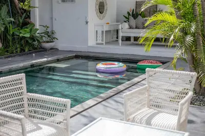 a swimming pool with two chairs and a table at Villa Stella Belle Seminyak in Seminyak