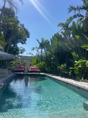 a swimming pool in a resort with chairs and trees at Villa Stella Belle Seminyak in Seminyak