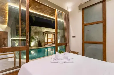 a bedroom with a pool seen through a window at Erianthe Peaceful 3 BR Private Pool Villa in Kerobokan