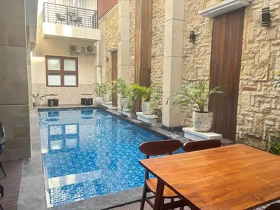 a large swimming pool with a wooden table and a wooden tableasteryasteryasteryastery at Ultimate Residence in Seminyak
