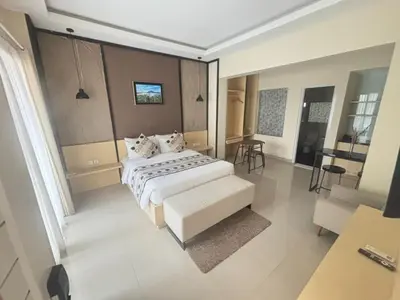 a bedroom with a large white bed and a chair at Ultimate Residence in Seminyak