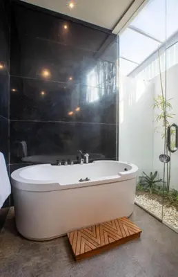 a bath tub sitting on a wooden floor in a bathroom at Mahita Garden Villa 3 Bedroom with Amazing view in Jimbaran