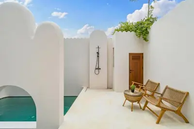 a patio with chairs and a table and water at Omarosa Stunning 3 BR Private Pool Villa in Kerobokan
