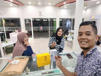 a man taking a picture of two women in a store at Joand Skyline in Seminyak