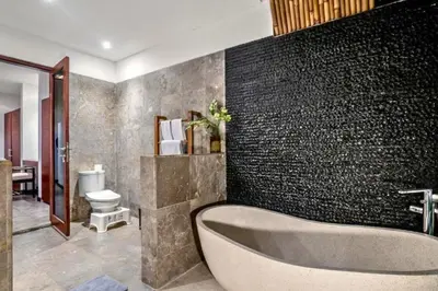 a bathroom with a tub and a black wall at Monique 3 BR Private Pool Villa in Seminyak
