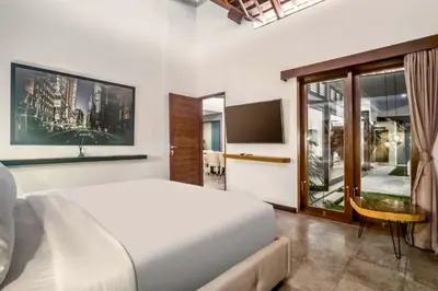 a bedroom with a white bed and a tv at Monique 3 BR Private Pool Villa in Seminyak