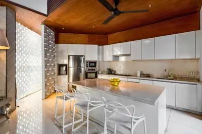 a kitchen with white cabinets and a ceiling fan at Sayara Modern 3 BR Private Pool Villa in Seminyak