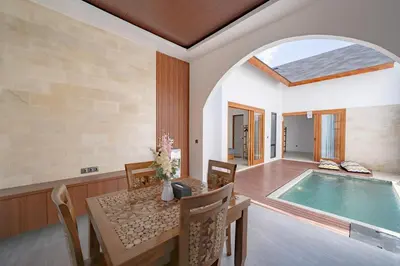a dining room with a table and a swimming pool at Il Petrucino Villa by Damaresa in Nusa Dua