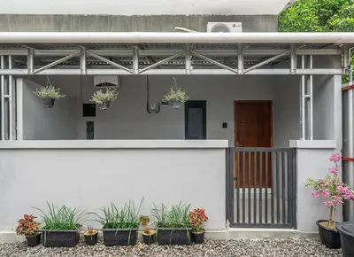 a white house with potted plants in front of it at Cozy Mezzanine Near Airport & Jimbaran Beach in Ngurah Rai International Airport