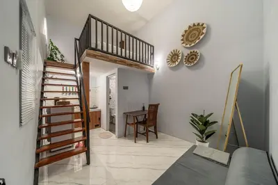 a living room with a staircase and a table at Cozy Mezzanine Near Airport & Jimbaran Beach in Ngurah Rai International Airport