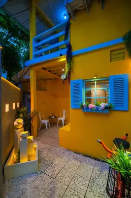 a yellow house with blue shutters and a patio at Palm Villa 4 , Seminyak Center in Seminyak