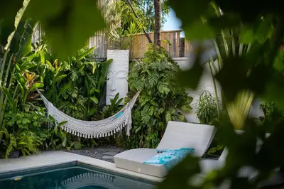 a hammock in a garden next to a swimming pool at Villa 888 Eat Shop Play - 3BR Private Pool Oberoi in Seminyak