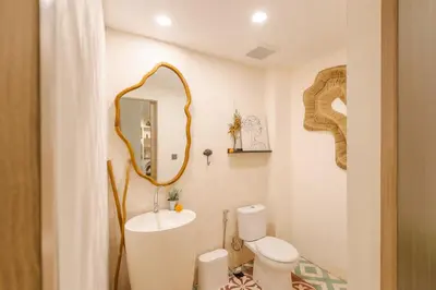 a bathroom with a sink and a mirror and a toilet at The Shalak Villa Bali in Denpasar