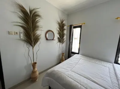 a bedroom with a bed and two plants in vases at Chandra's house in Pesanggaran