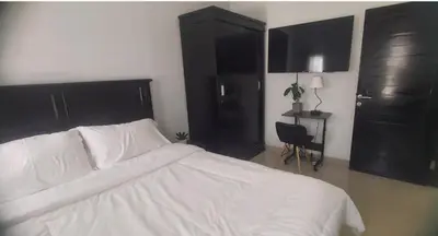 a bedroom with a white bed and black cabinets at Chandra's house in Pesanggaran