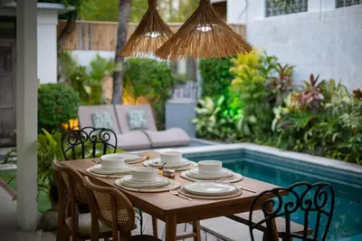 a wooden table with chairs and cups and plates on it at Villa GR888 - 3BR Tropical Comfort Seminyak in Seminyak