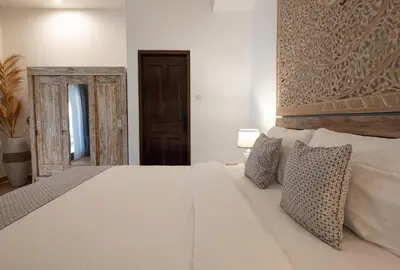 a bedroom with a white bed with a wooden headboard at 2BR Villa - Central Seminyak - Private Cook & Breakfast in Seminyak