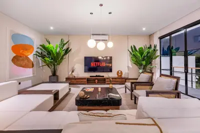 a living room with white furniture and a flat screen tv at Villa Rice Kerobokan in Kerobokan