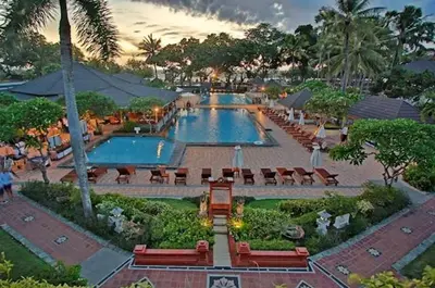 a large swimming pool with tables and chairs in a resort at The Beach Residence at Jayakarta Resort Bali in Seminyak