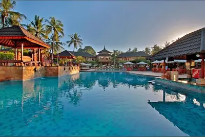 a swimming pool at a resort with palm trees at The Beach Residence at Jayakarta Resort Bali in Seminyak