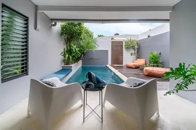 a swimming pool in a house with two chairs and a table at Villa 111 - Romantic 1BR Villa in Batu Belig in Seminyak