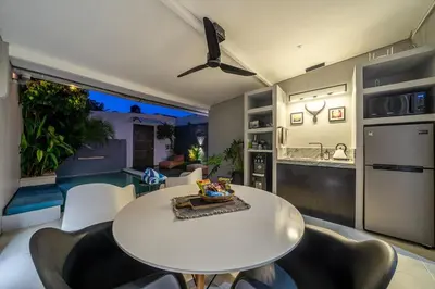 a kitchen and living room with a white table and chairs at Villa 111 - Romantic 1BR Villa in Batu Belig in Seminyak