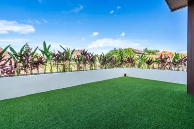 an empty backyard with a white fence and green grass at New Villa 3BR Umalas Pool Near Seminyak and Canggu in Canggu