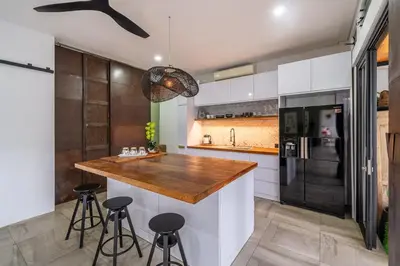 a kitchen with a counter with a refrigerator and stools at Villa 121 - Modern 1BR Villa Near Batu Belig Beach in Seminyak