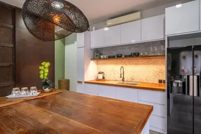a kitchen with a wooden table and a refrigerator at Villa 121 - Modern 1BR Villa Near Batu Belig Beach in Seminyak