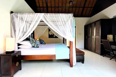 a bedroom with a canopy bed with white curtains at Superb and Elegant 3-Bedroom Villa Close to the Beach in Seminyak