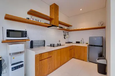 a kitchen with wooden cabinets and a microwave and a refrigerator at Private 3BR Villa Sweetie with Pool Seminyak in Seminyak