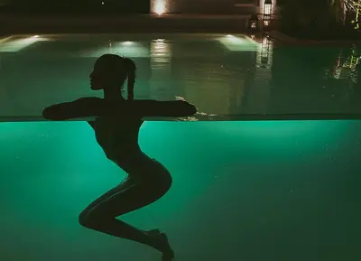 a silhouette of a woman swimming in a pool at The Turiya - Redefining luxury in Canggu in Canggu