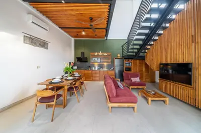 a living room with a table and chairs and a television at Lindt - 3BR Villa with Private Pool and Ricefield View in Canggu