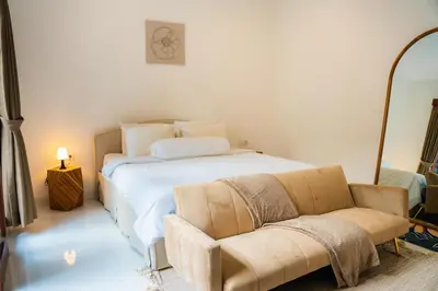 a bedroom with a white bed and a chair at Satori Villa Umalas in Canggu